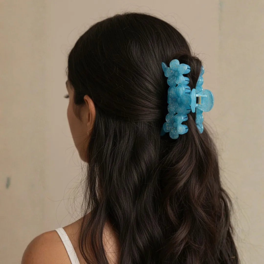 A woman wearing a large blue floral hair clip in a half-up, half-down hairstyle for an effortless 2026 aesthetic.