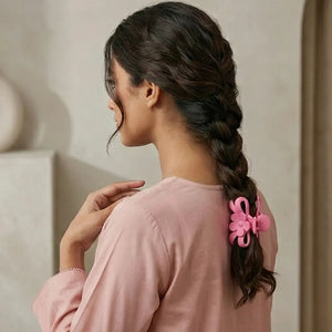Woman with long braid wearing pink matte flower and bow hair claw clip
