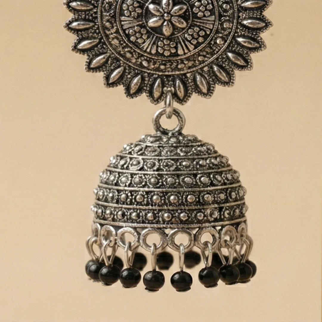 Detailed close-up of the floral sunburst stud and intricate metalwork on the oxidized silver jhumka.