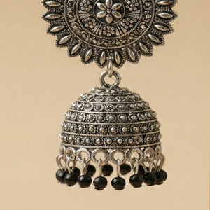 Detailed close-up of the floral sunburst stud and intricate metalwork on the oxidized silver jhumka.