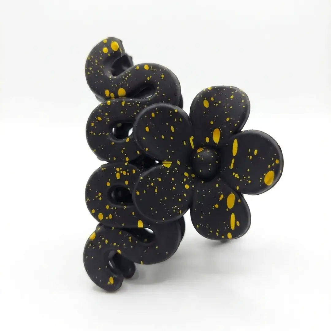 Side view of black artistic hair catcher with gold paint splatter and floral design.