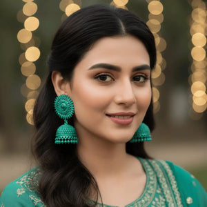 A woman wearing vibrant sea green crystal jhumkay styled with a matching green ethnic outfit for a festive Pakistani look