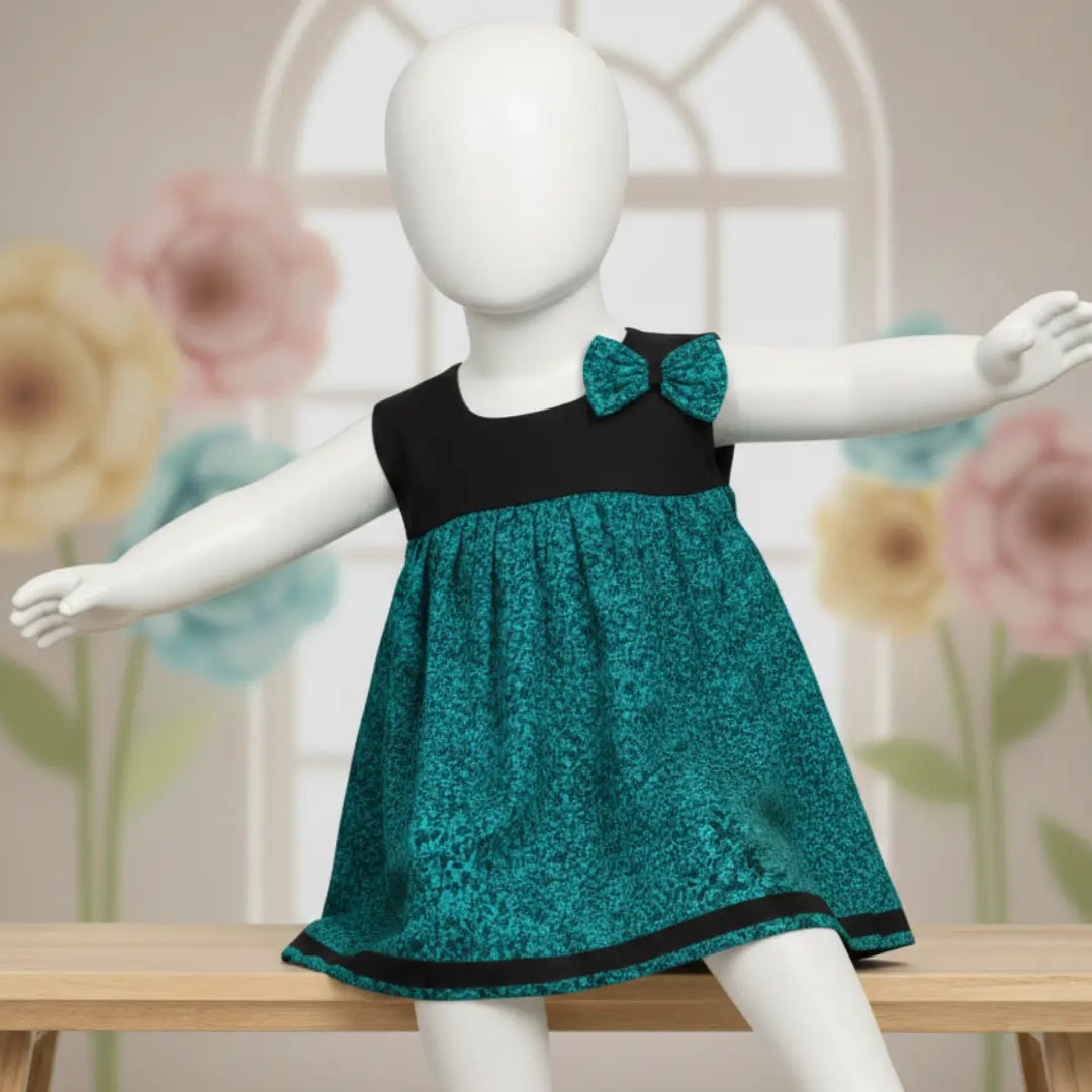 Toddler girl wearing teal and black sleeveless cotton frock with shoulder bow detail.