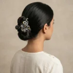 Woman wearing a matte black and gold speckled flower hair claw clip in a neat bun hairstyle.