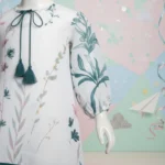 White teal botanical girls tunic close-up showing teal floral print and tassel neckline