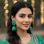 A woman wearing vibrant sea green crystal jhumkay styled with a matching green ethnic outfit for a festive Pakistani look