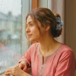 Dusty blue floral acrylic hair claw clip securing a messy bun on a South Asian model looking out a rainy window, by Applique Threads.